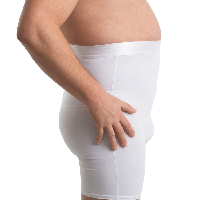 En man bär ett vitt kompressionsbälte i shortsmodell och ses från sidan med handen på höften mot en vit bakgrund.