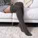 En person som bär mörkgrå, knähöga Cozysocks med flätstickat mönster.