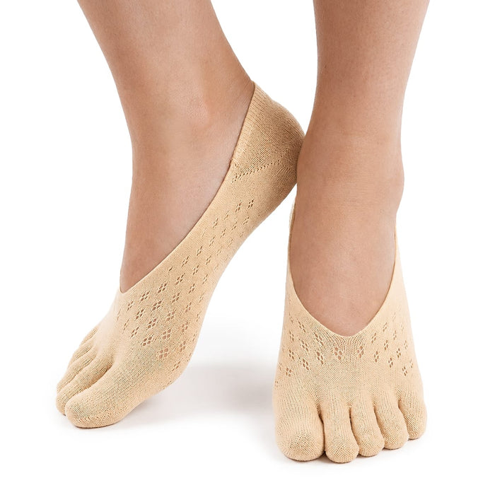 Fötter med beige, låga tåstrumpor från Kroppsbutiken, hallux valgus-stöd, hålmönster och lätt tåseparation.