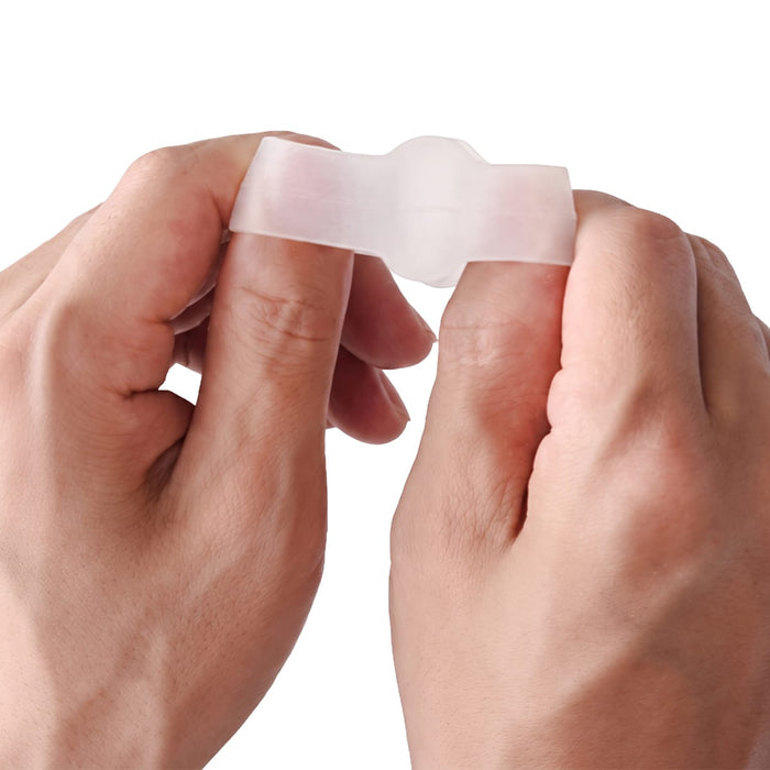 Två händer håller Kroppsbutikens tåseparatorer (2 st) mot en vit bakgrund; de är avsedda att lindra besvär vid hallux valgus.