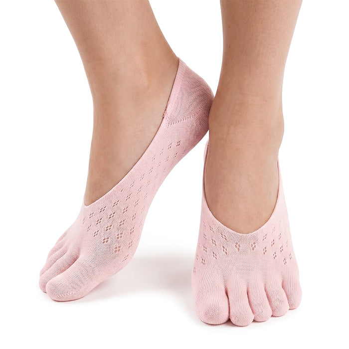 En person med ljusrosa, låga tåstrumpor med tåseparatorer för hallux valgus avbildas mot en vit bakgrund.