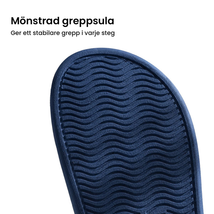 Närbild på blå zonterapitofflar med vågig sula och knubbigt mönster för fotstimulering och stabilt grepp.