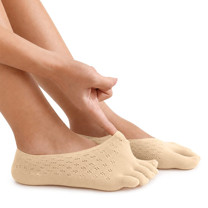 Personen justerar en beige tåstrumpa med handen; strumpan har inbyggt stöd för hallux valgus.
