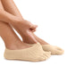 Personen justerar en beige tåstrumpa med handen; strumpan har inbyggt stöd för hallux valgus.