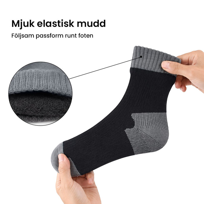 Två händer visar en svart och grå vattentät strumpa från Kroppsbutiken, med svensk text ovanför mudden.