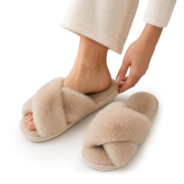 En person i ljusa hemkläder provar ett par vintertofflor från Kroppsbutiken och håller i en beige, mjuk toffel.