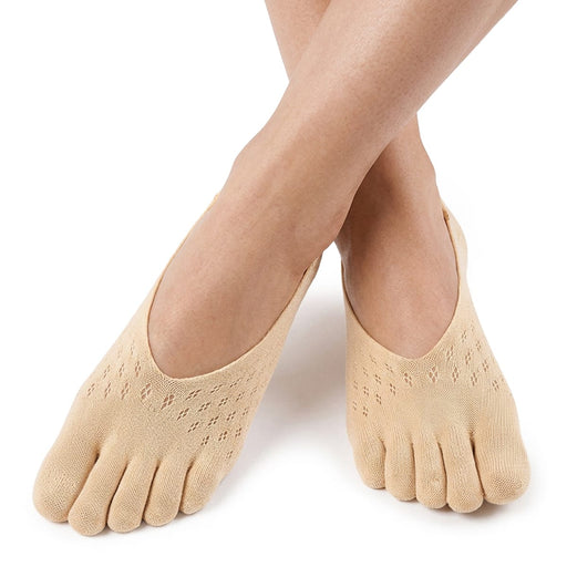 Personen har på sig låga tåstrumpor med stöd för hallux valgus, och fötterna är korsade mot en vit bakgrund.