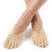 Personen har på sig låga tåstrumpor med stöd för hallux valgus, och fötterna är korsade mot en vit bakgrund.