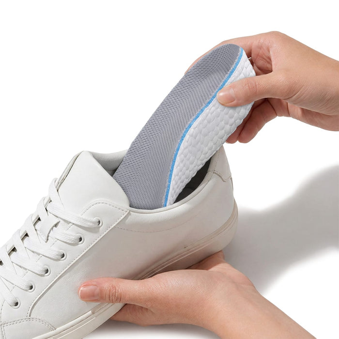 En person lägger med handen in en höjdhöjande inläggssula från Kroppsbutiken i en vit sneaker.